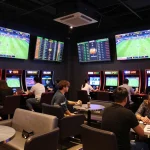 Excited bettors engaging with VB88 SPORT in a vibrant sports betting lounge atmosphere