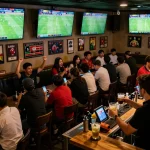 Tỷ lệ kèo nhà cái 5 actively being analyzed by enthusiastic fans in a crowded sports bar.