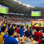 Fans celebrating with tỷ lệ kèo bóng đá displays during a thrilling football match in the stadium.