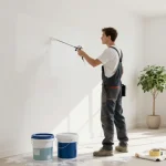 Professionele schilder die latex spuiten aanbrengt in een lichte moderne woonkamer, en de kwaliteit van de wandafwerking toont.